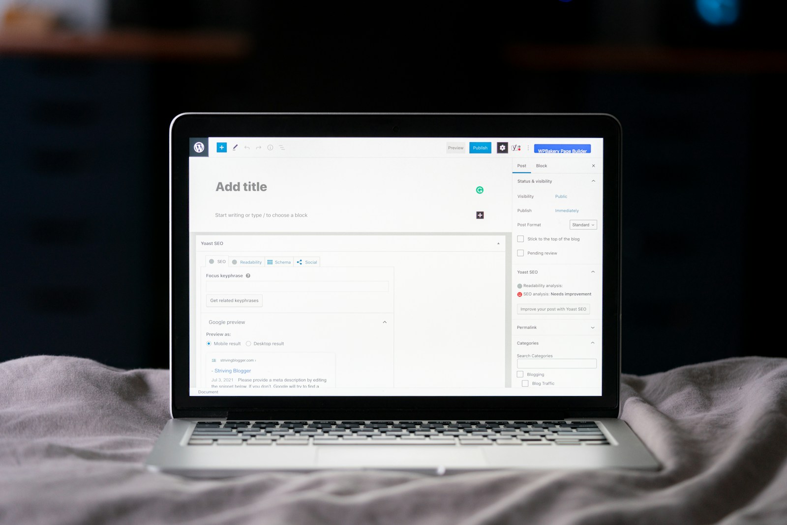 A laptop on a bed showing the WordPress block editor with an empty Add title field and the Yoast SEO panel