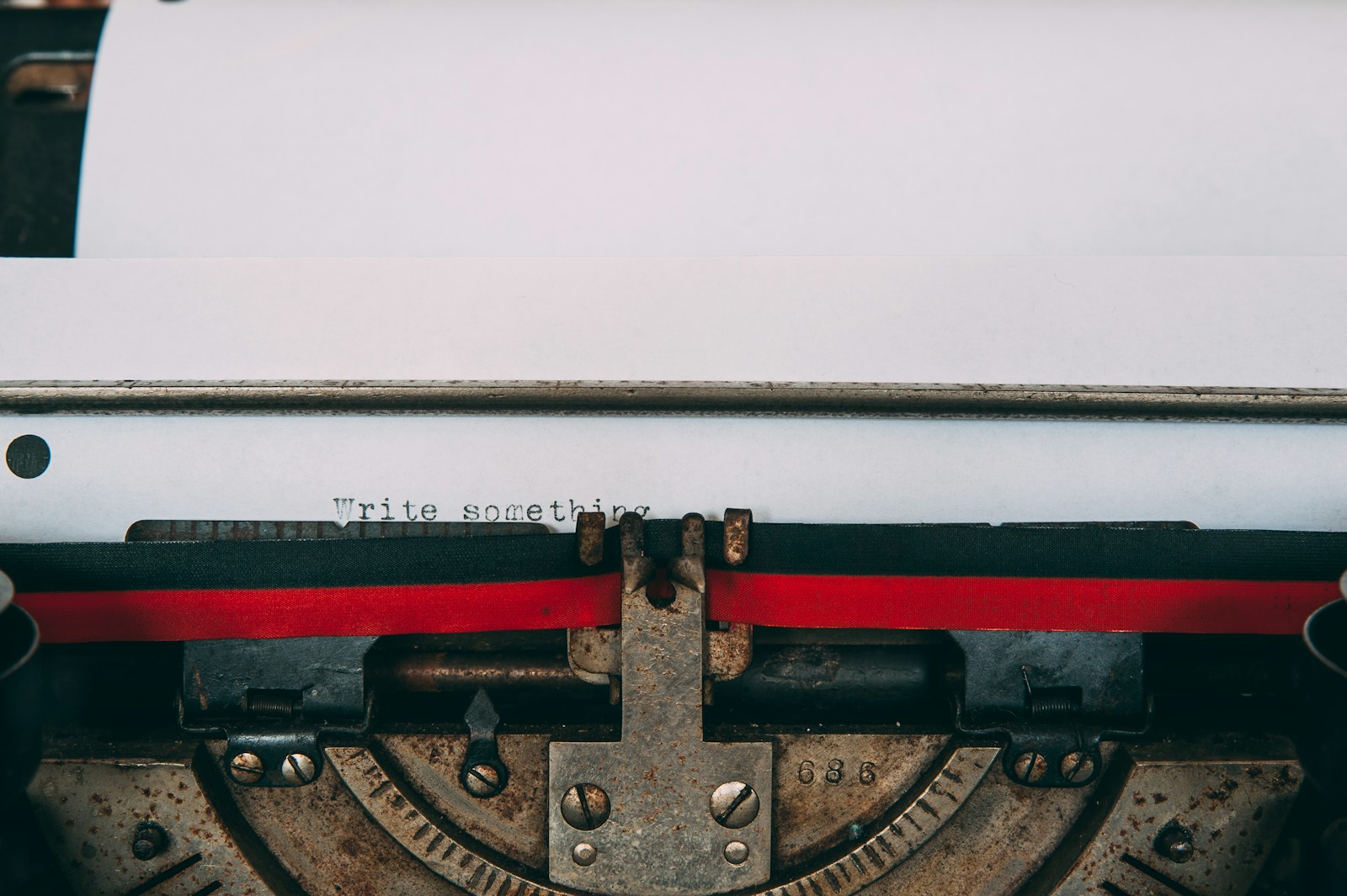 Close-up of an old typewriter with a sheet of paper on which the words Write something are typed