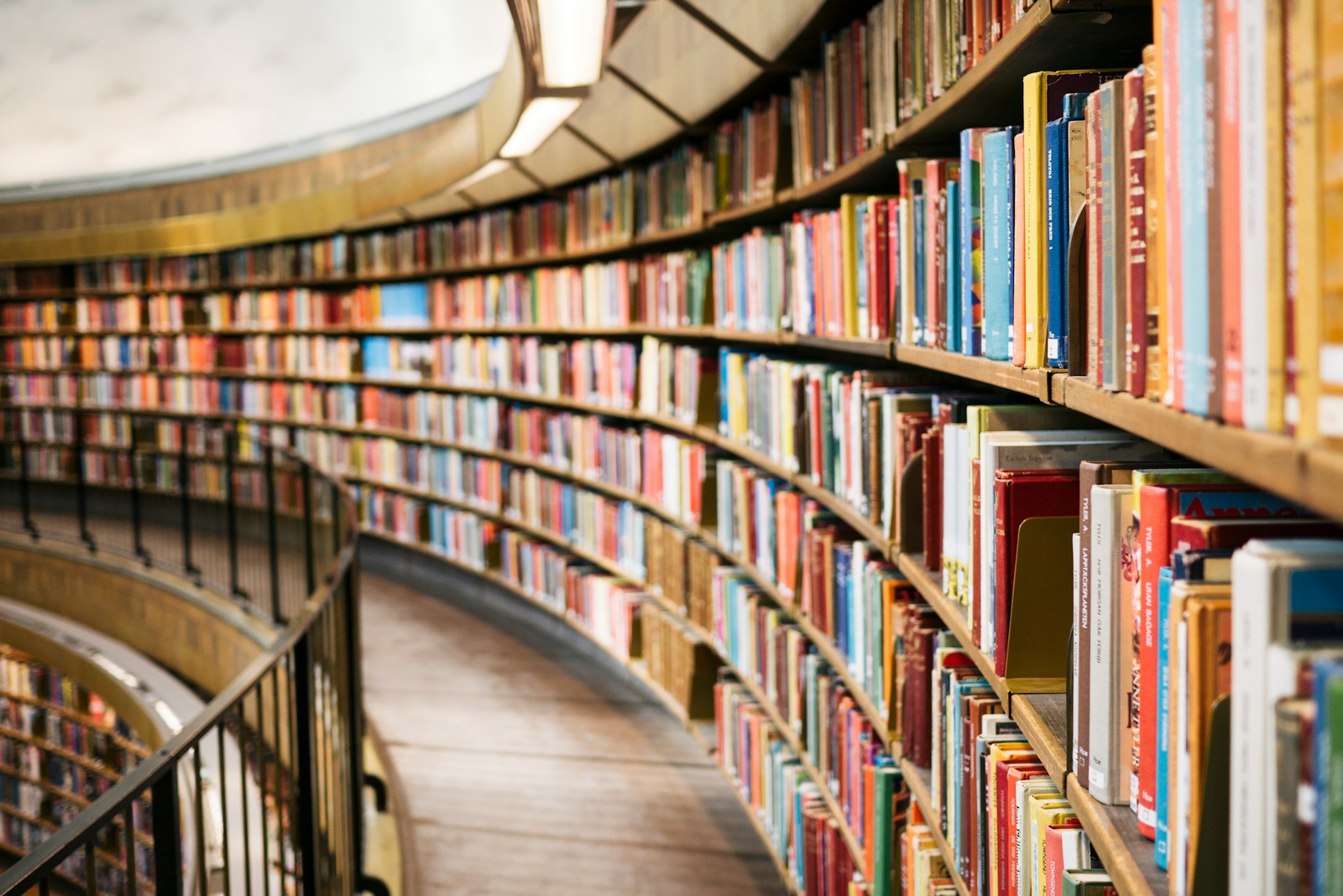 Curved library shelves packed with colourful books receding along a walkway